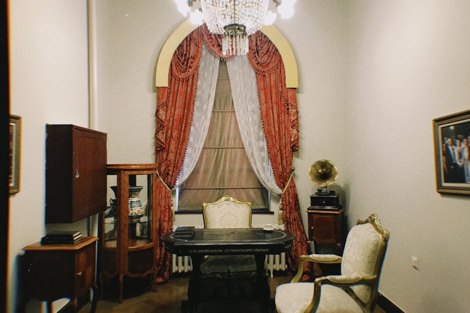 A beautifully decorated vintage living room featuring classic furniture and elegant red drapes.